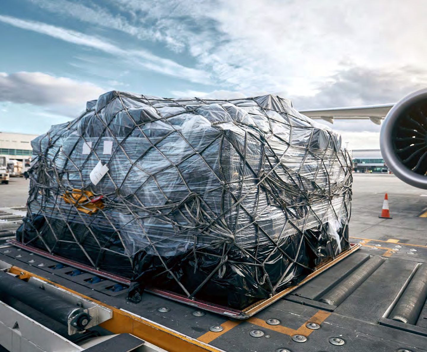 Netted air cargo pallet being loaded beside an aircraft engine